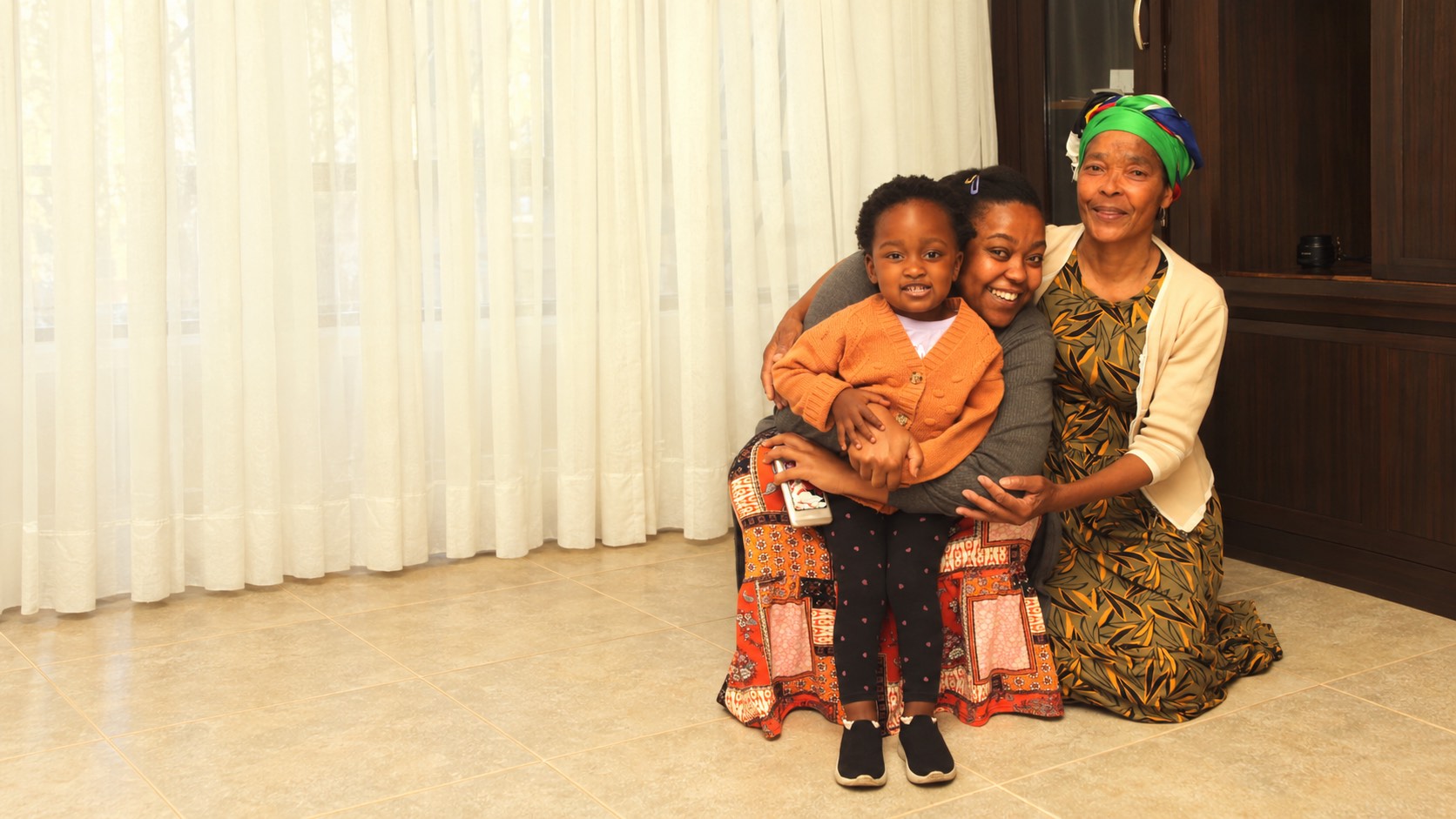 A grandmother, mother and child gathered together at home